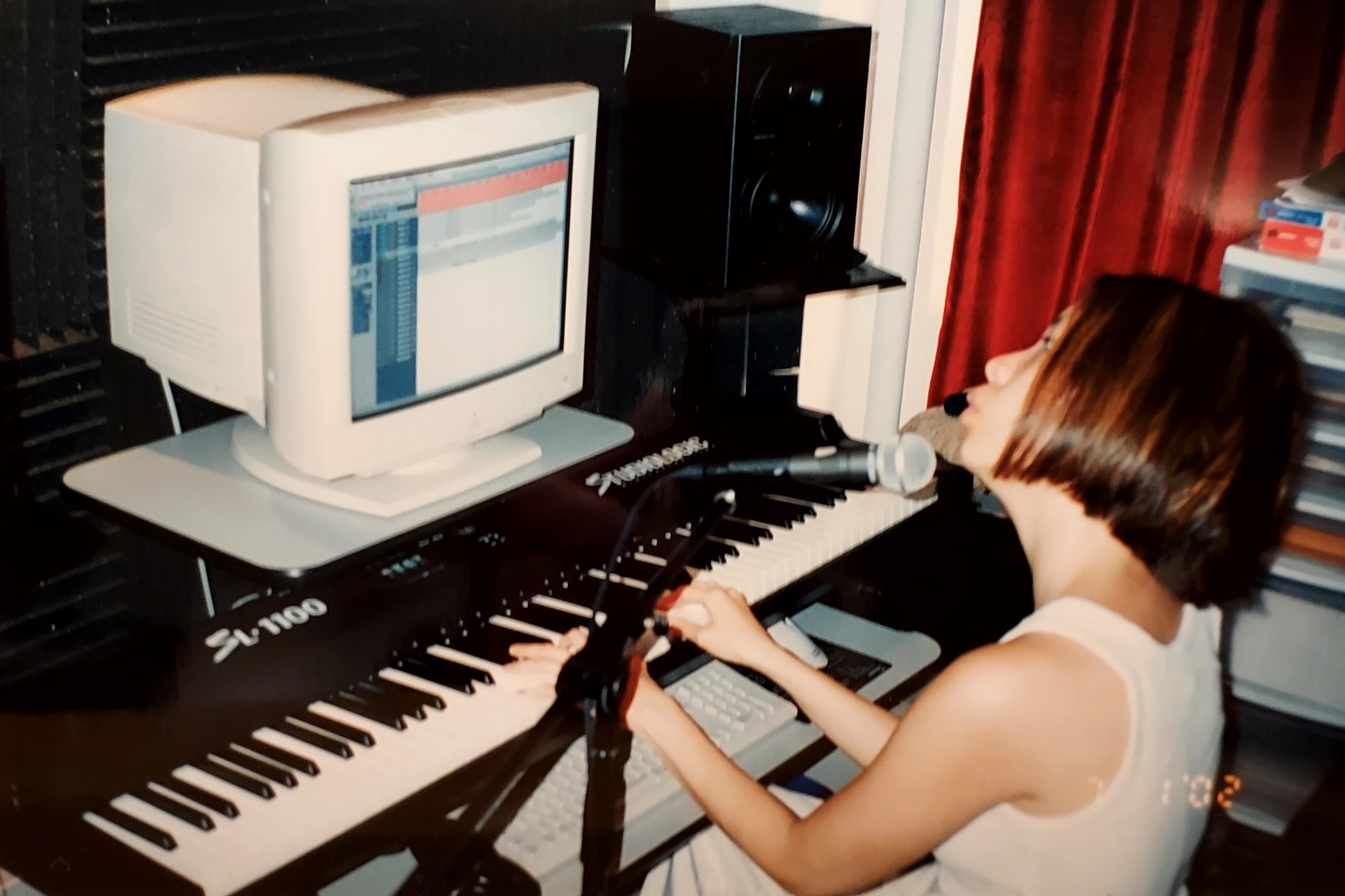 Sophia singing into a mic and playing piano in front of computer