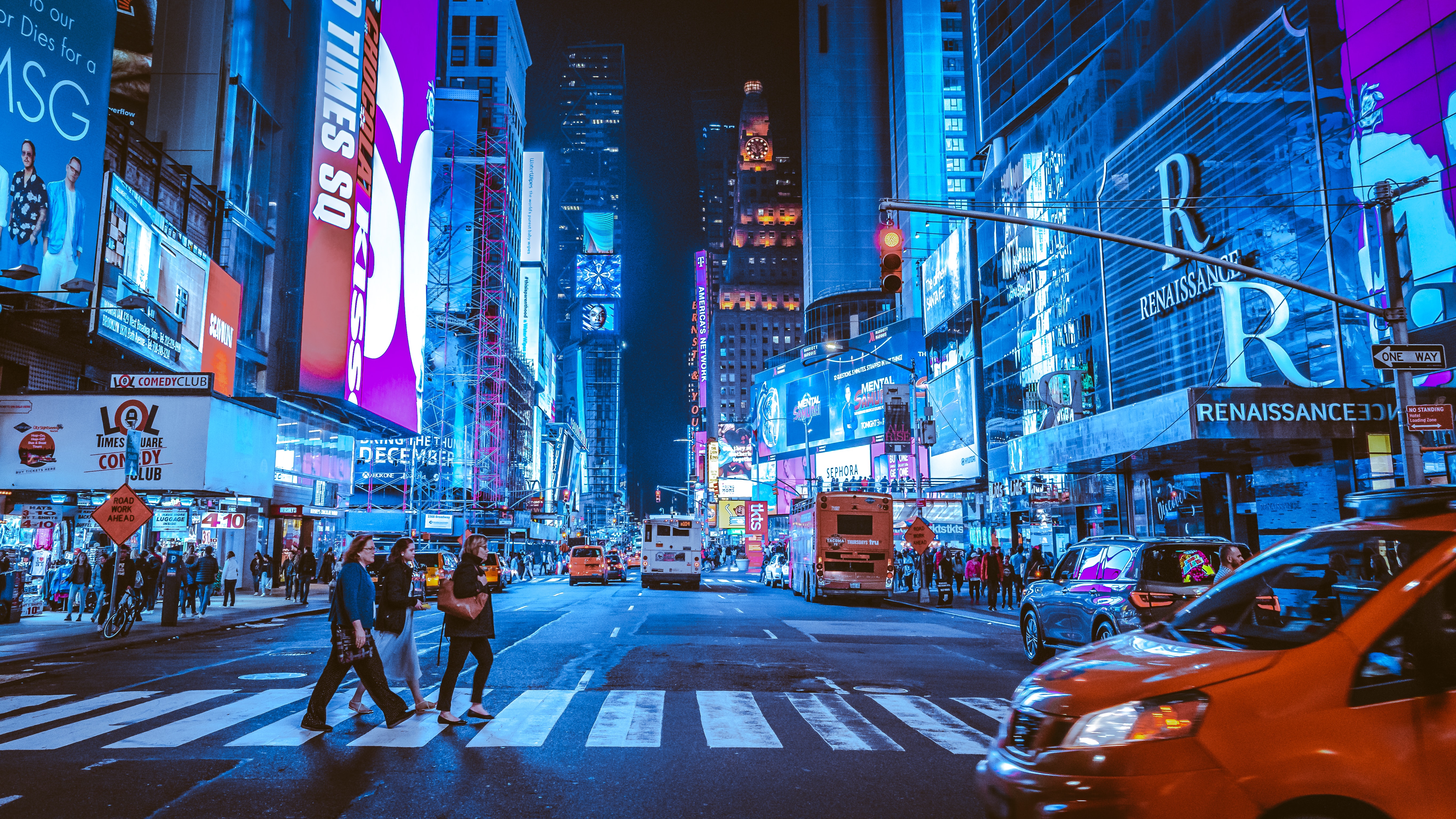 Three people walking on a crosswalk in Times Square, NYC